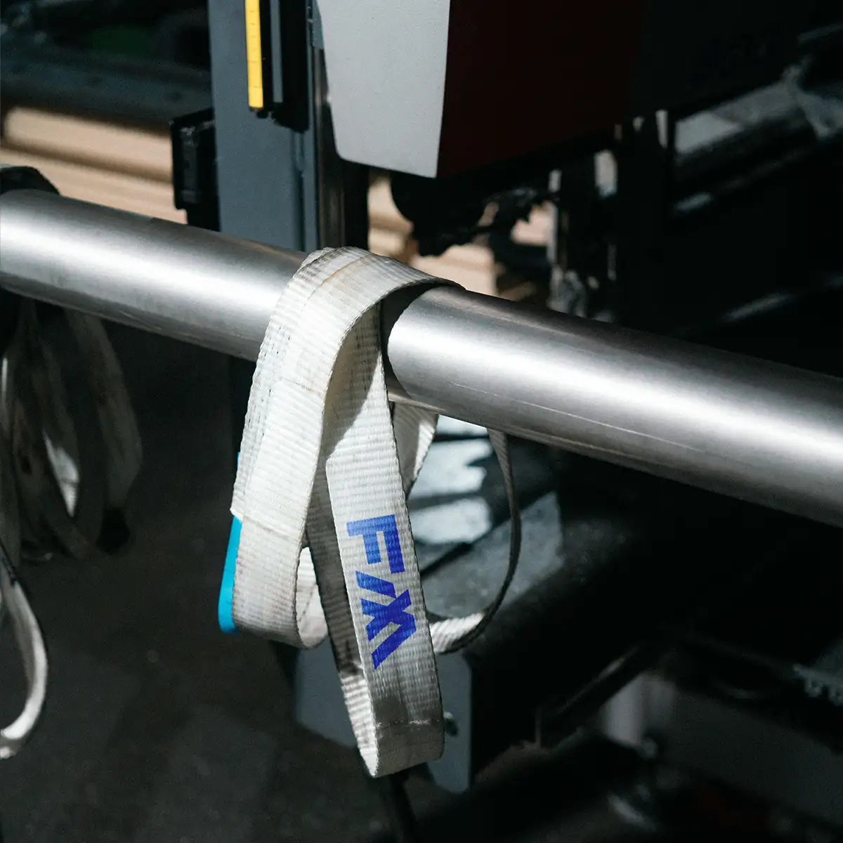 Weißer Spanngurt mit Fix Metall Logo an einer Metallröhre.