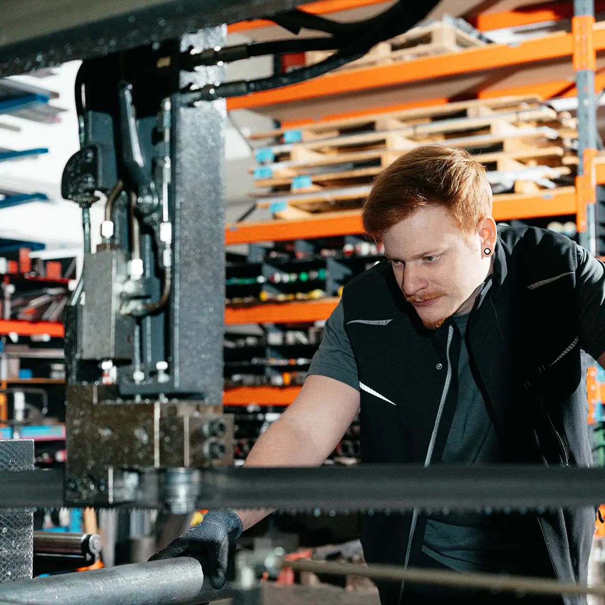 Arbeiter bedient eine Metallbandsäge in einer Werkstatt.
